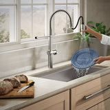 Person washing a blue plate under a modern kitchen faucet with a view of bread on a cutting board.