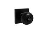 Black finish square plate entrance round knob with a keyhole on the front and a metallic interior mechanism.